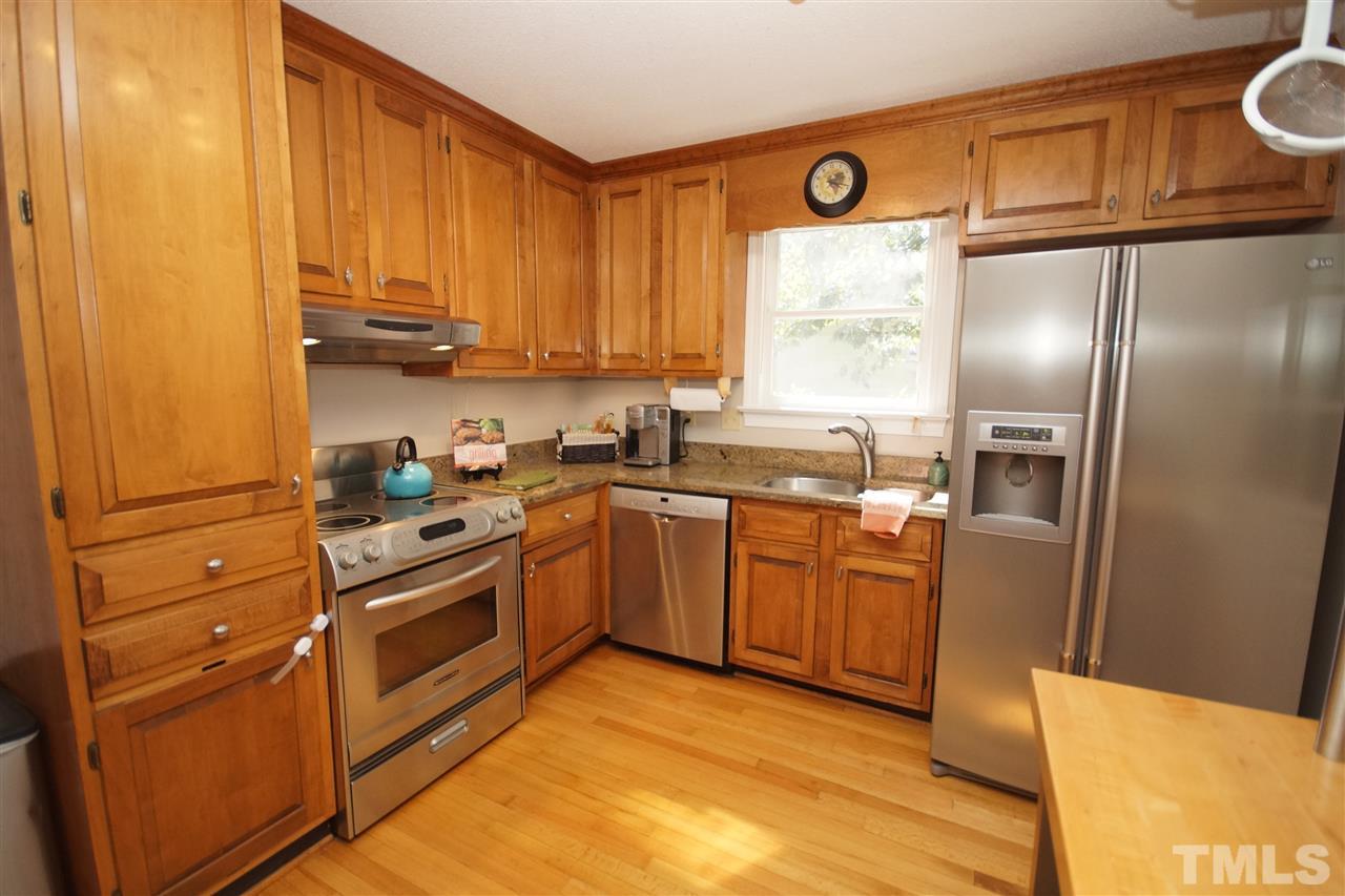 7033 Sandringham Court Raleigh, NC 27613 - Photo 9 of 25 a kitchen with stainless steel appliances granite countertop a refrigerator a sink dishwasher a stove with wooden cabinets and floor