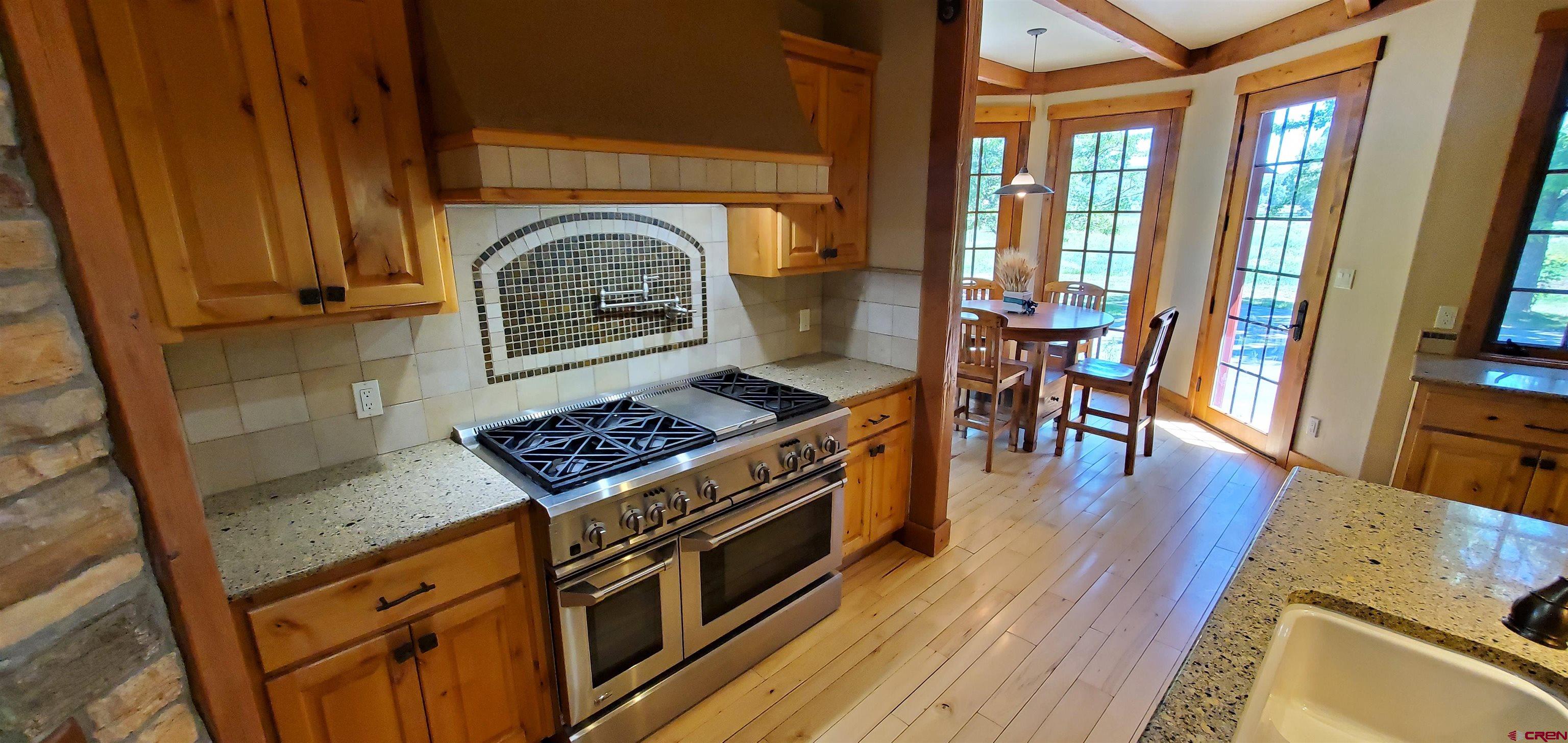 80 Twilight Trails Circle Durango, CO 81301 - Photo 8 of 26 a kitchen with stainless steel appliances granite countertop a stove a refrigerator a dining table and chairs with wooden floor
