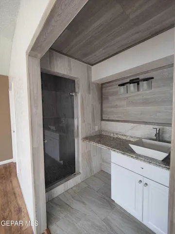 a view of a hallway with wooden floor and a bathroom