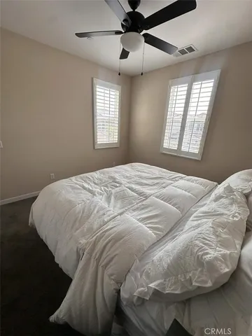 a large bed sitting in a bedroom next to a window and a chandelier