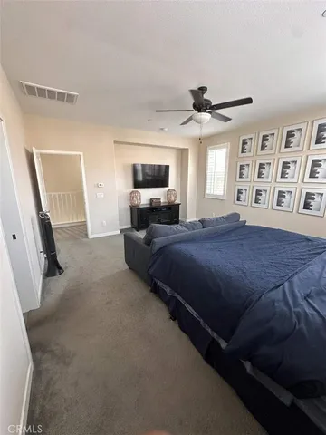 a spacious bedroom with a bed window and flat screen tv