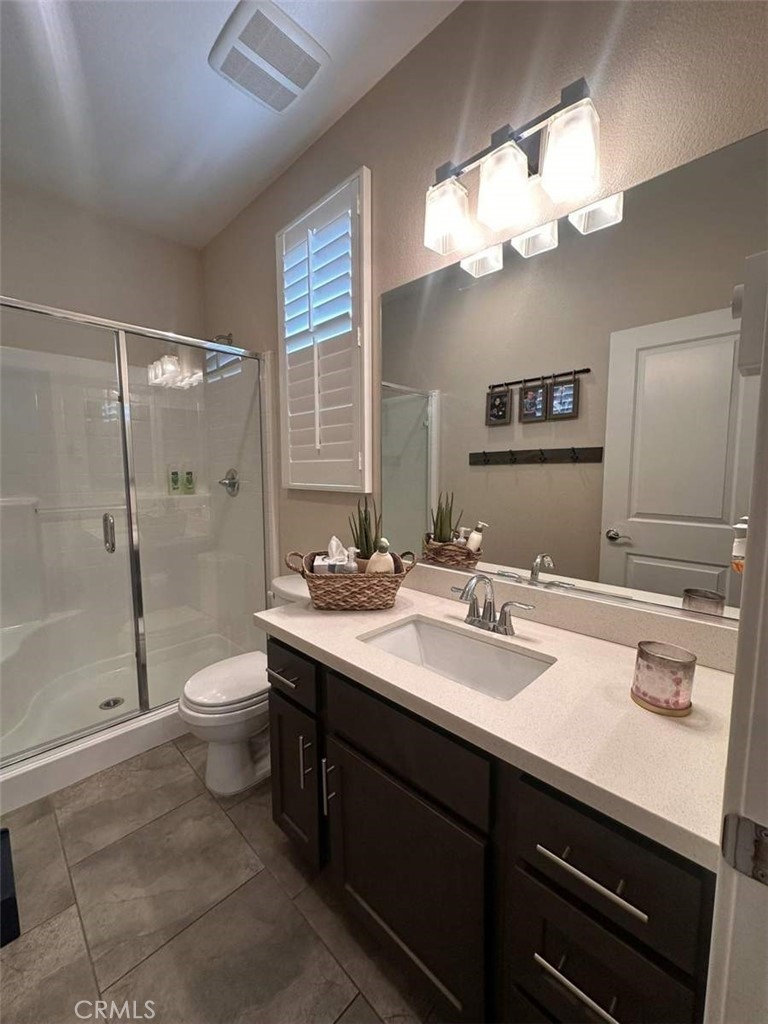 39552 Strada Scala Lake Elsinore, CA 92532 - Photo 6 of 40 a bathroom with a sink a toilet a large mirror and shower