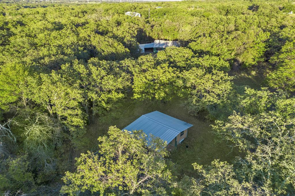 199 Cheyenne Trail Springtown, TX 76082 - Photo 20 of 22 Aerial perspective showcasing a verdant landscape with extensive tree coverage and two structures featuring metal roofs