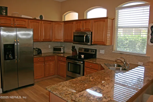 a kitchen with stainless steel appliances granite countertop a stove a sink and a microwave