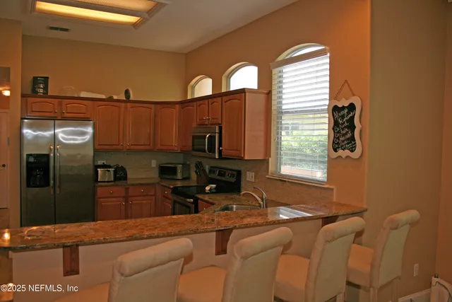 a kitchen with stainless steel appliances granite countertop a refrigerator and a stove top oven