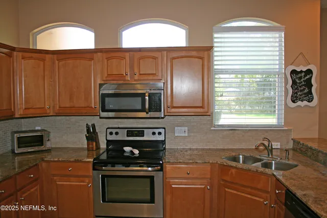 a kitchen with stainless steel appliances granite countertop a stove a sink and a microwave