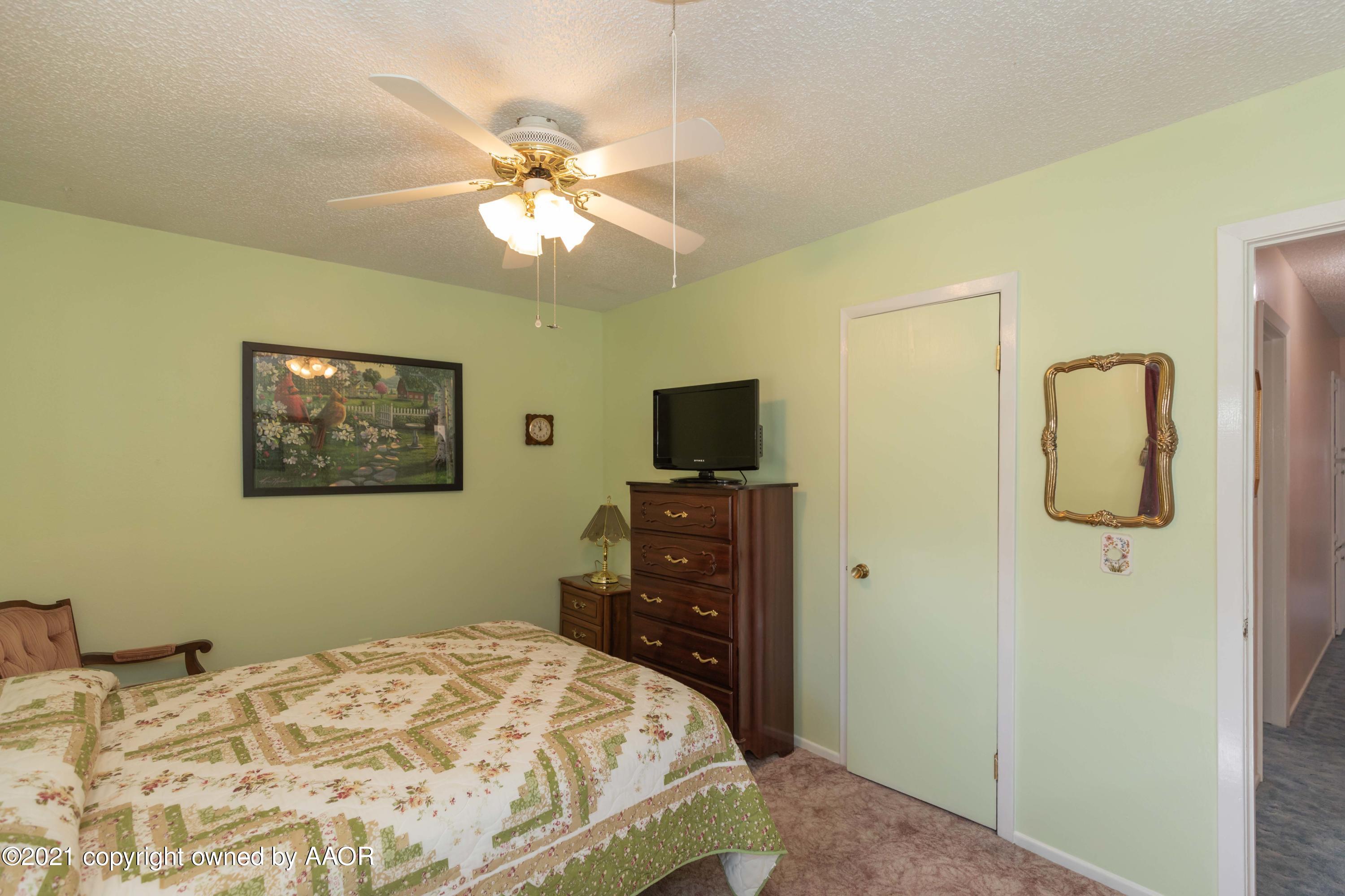 5104 McCarty Boulevard Amarillo, TX 79110 - Photo 19 of 35 a bedroom with a bed and a flat tv screen on dresser