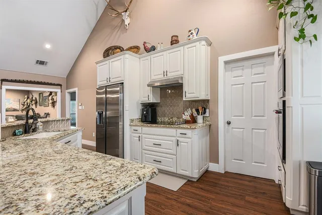 a kitchen with stainless steel appliances kitchen island granite countertop a refrigerator and a stove top oven
