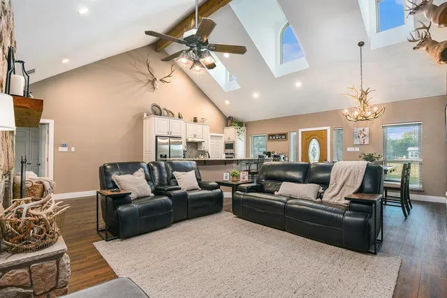 a living room with furniture kitchen view and a chandelier