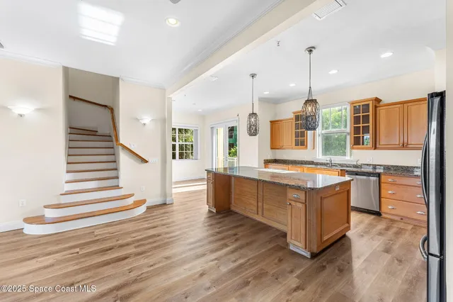 a large kitchen with stainless steel appliances kitchen island granite countertop a large counter top and wooden floors