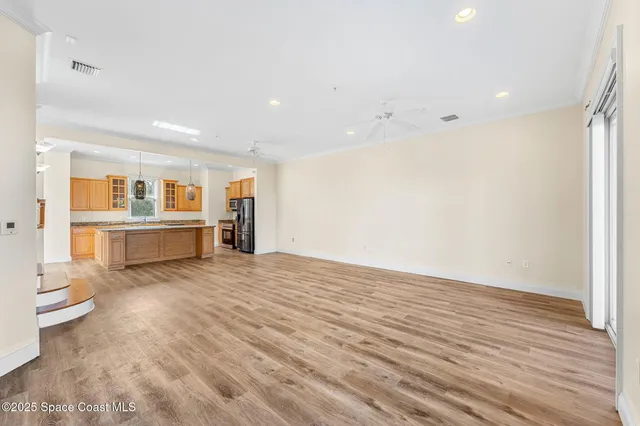 a view of a kitchen and an empty room with wooden floor