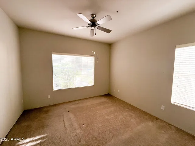 an empty room with a window and a ceiling fan