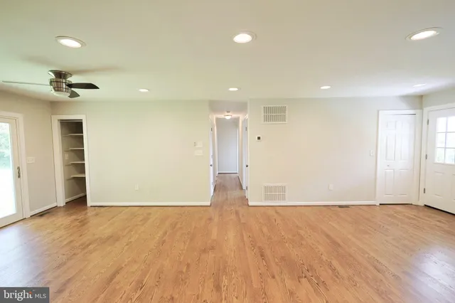 an empty room with wooden floor and a ceiling fan