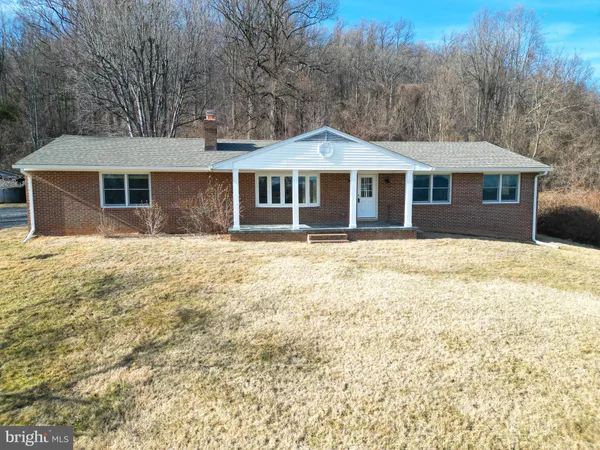 a front view of house with yard and trees in the background