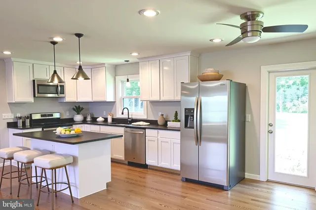 a kitchen with stainless steel appliances granite countertop a sink a stove a refrigerator cabinets and wooden floor