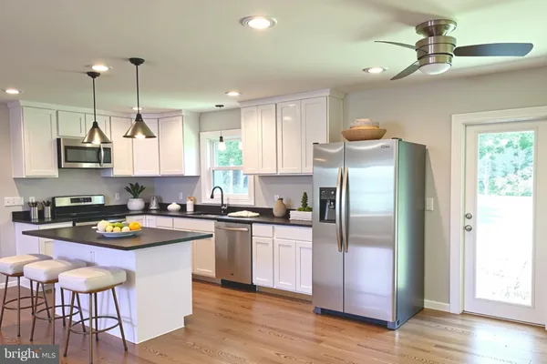 a kitchen with stainless steel appliances granite countertop a sink a stove a refrigerator cabinets and wooden floor