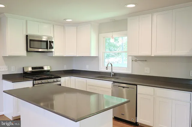 a kitchen with stainless steel appliances granite countertop a sink a stove and microwave