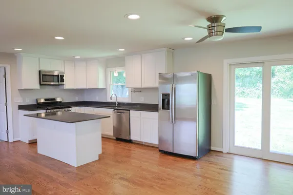a kitchen with stainless steel appliances granite countertop a refrigerator a sink a stove a microwave and island