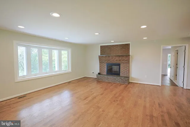 an empty room with wooden floor and a fireplace