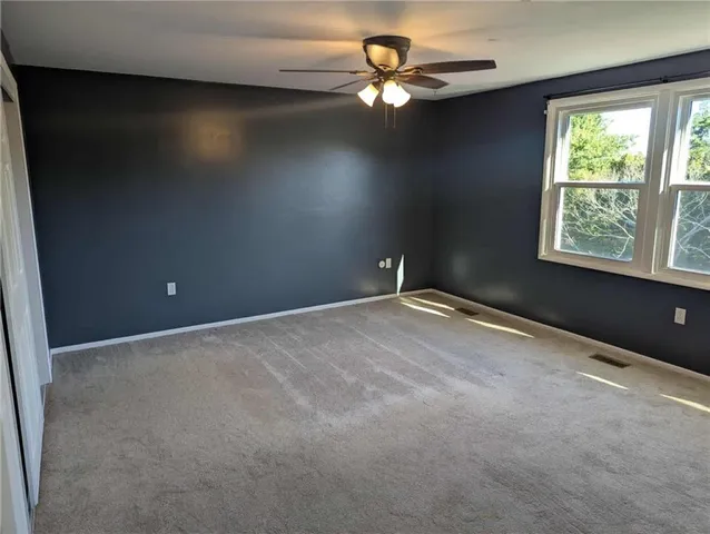 an empty room with a window and a fan