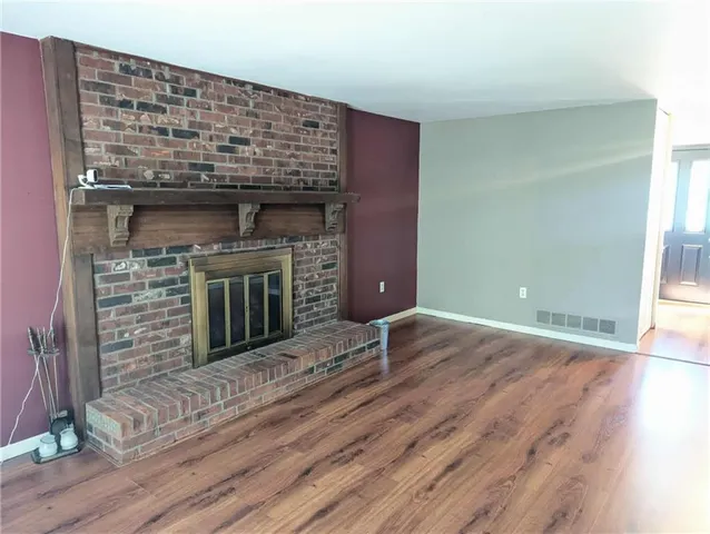 an empty room with wooden floor a fireplace and windows