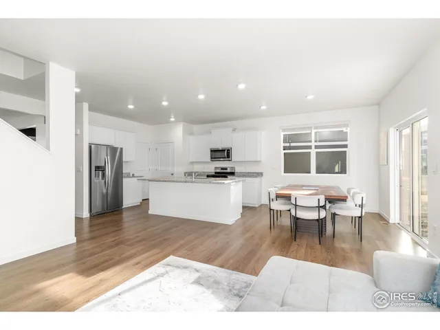 a living room with stainless steel appliances kitchen island granite countertop wooden floor a dining table and kitchen view