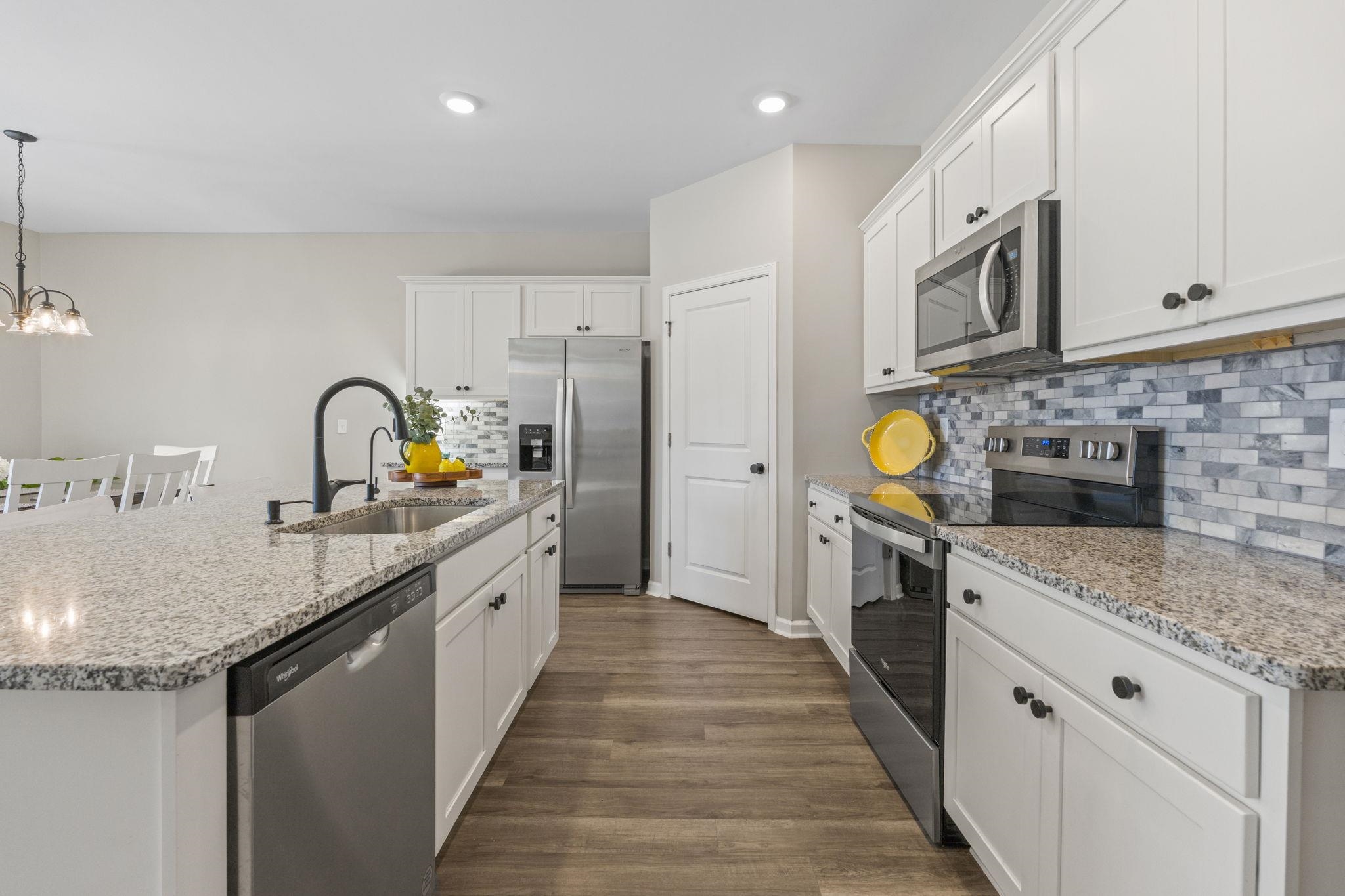 143 Ardeer Court Little River, SC 29566 - Photo 7 of 40 Kitchen featuring appliances with stainless steel finishes, white cabinets, a kitchen island with sink, light stone counters, and recessed lighting