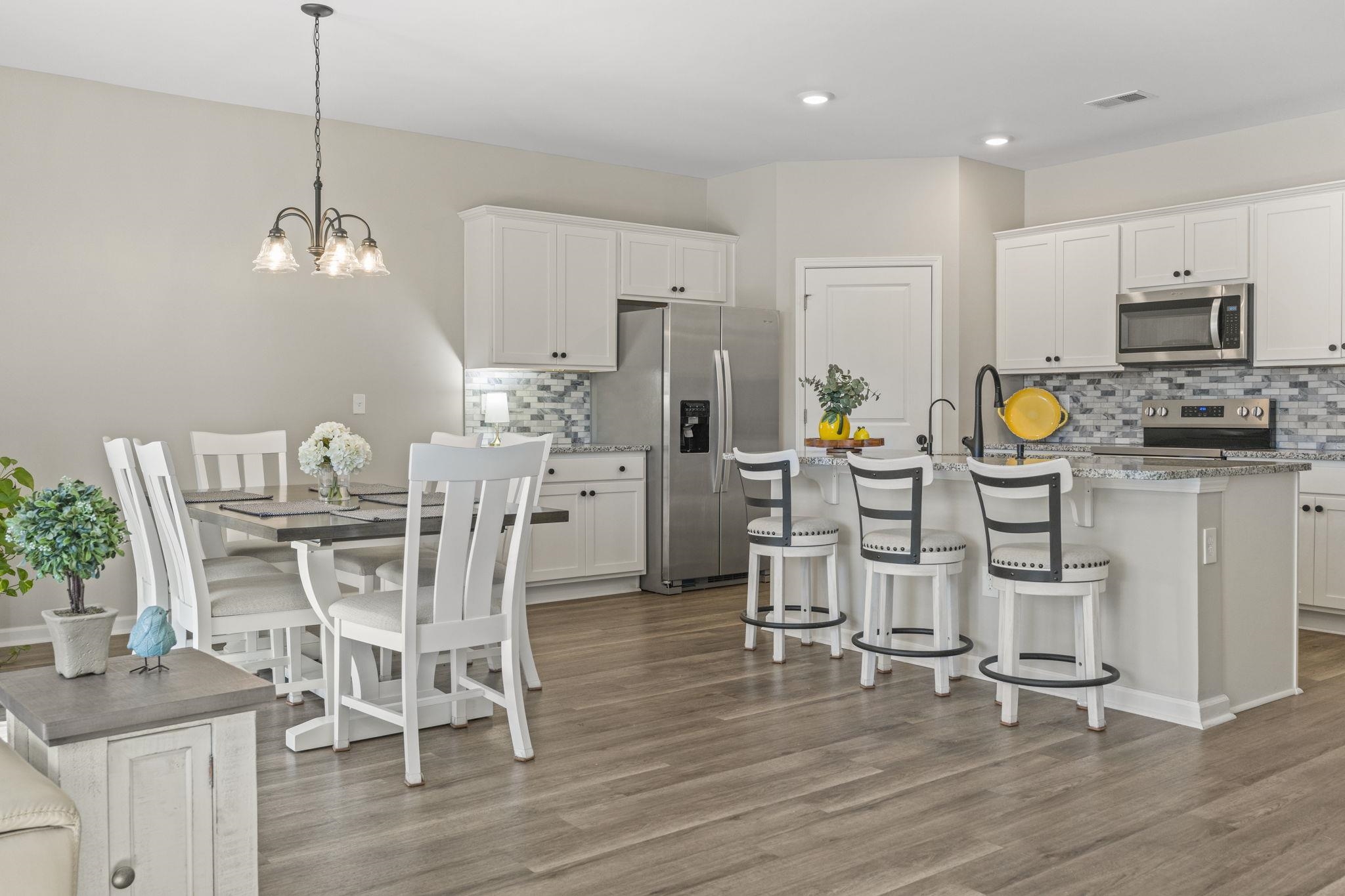 143 Ardeer Court Little River, SC 29566 - Photo 10 of 40 Kitchen with appliances with stainless steel finishes, white cabinets, a breakfast bar, a center island with sink, and hanging light fixtures