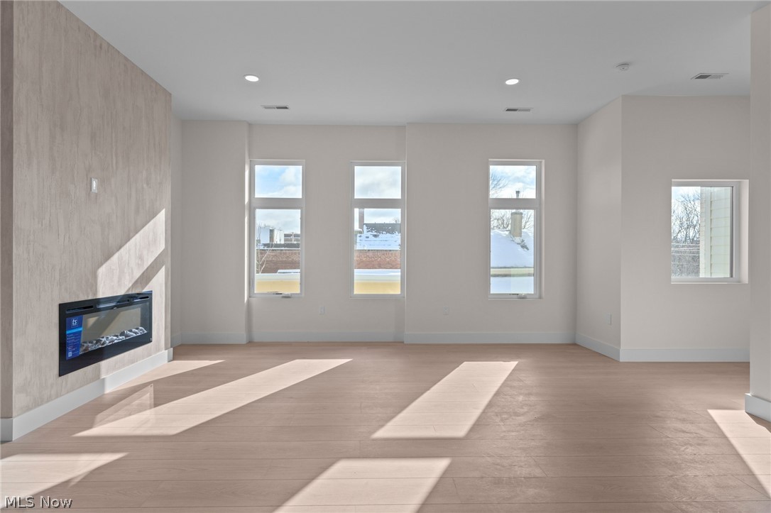 2149 Columbus Road Cleveland, OH 44113 - Photo 10 of 38 Unfurnished living room featuring light wood-type flooring, a glass covered fireplace, and recessed lighting