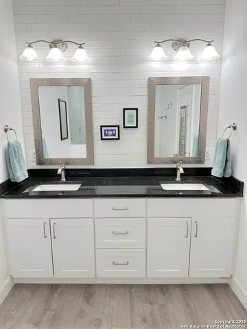 a bathroom with white cabinets sink and mirror