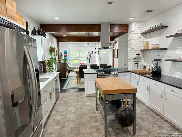 a kitchen with stainless steel appliances a refrigerator a sink a stove and cabinets