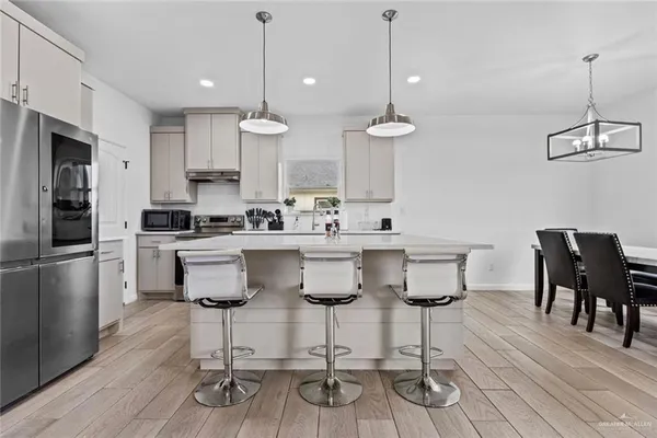 a kitchen with stainless steel appliances kitchen island granite countertop a dining table chairs and white cabinets