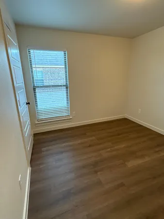 a view of a room that has wooden floor and a window