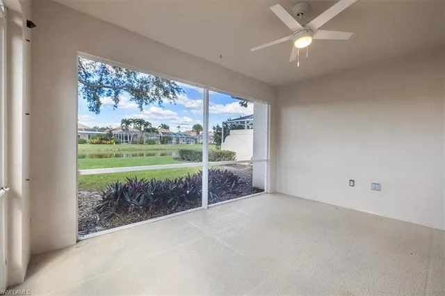an empty room with floor to ceiling windows and ceiling fan