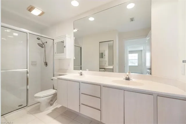 a bathroom with a double vanity sink toilet mirror and shower