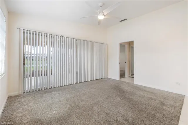 an empty room with a ceiling fan and a window