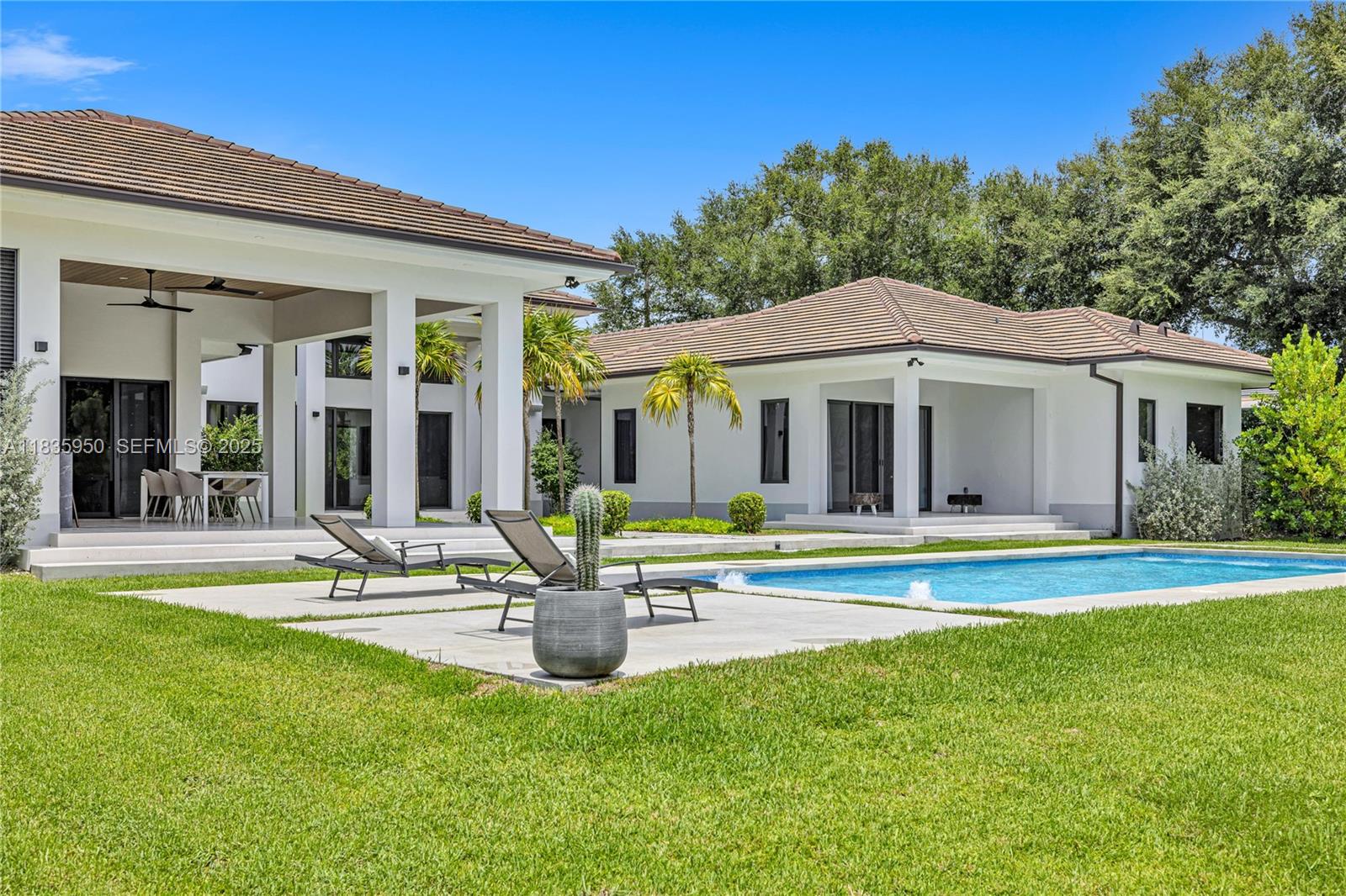 7699 Southwest 118th Street Pinecrest, FL 33156 - Photo 27 of 38 a front view of a house with swimming pool having outdoor seating