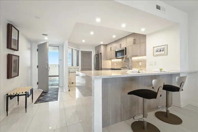 a kitchen with stainless steel appliances kitchen island granite countertop a dining table chairs and sink