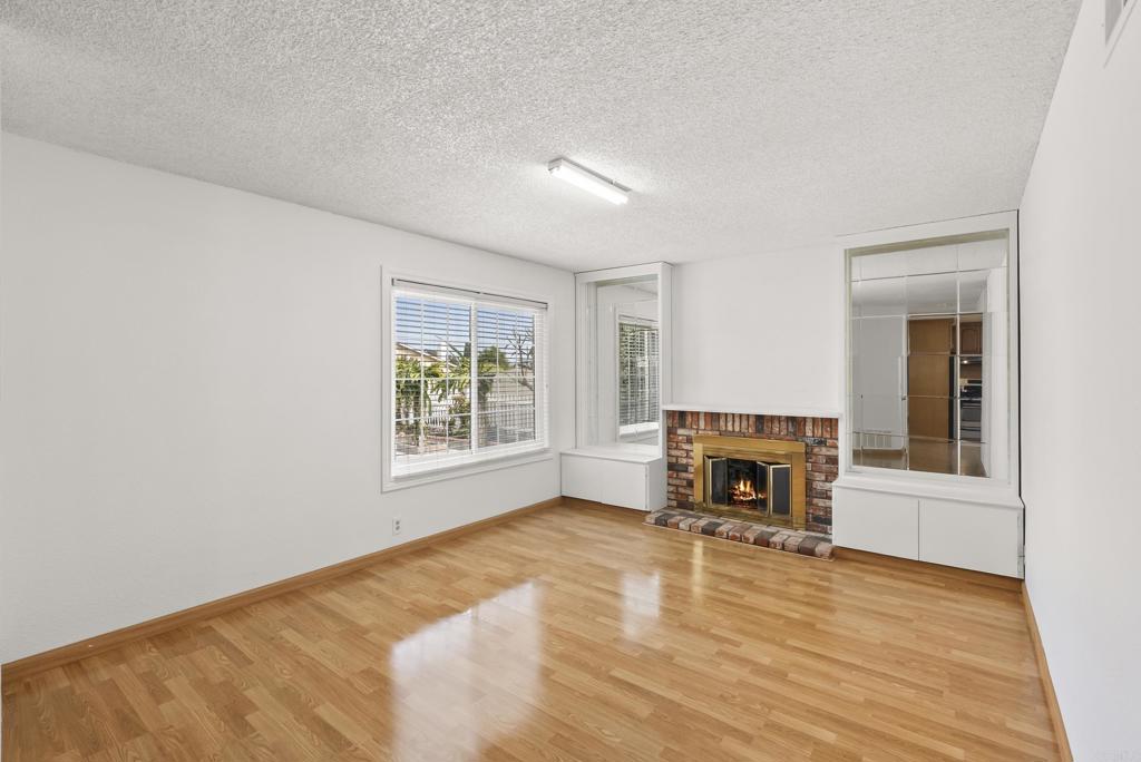 1850 Paradise Hills Road San Diego, CA 92114 - Photo 10 of 39 an empty room with windows fireplace and wooden floor