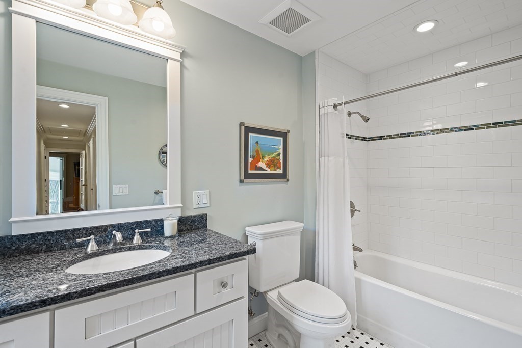 22 McCall Road Winchester, MA 01890 - Photo 29 of 40 a bathroom with a granite countertop sink a toilet a mirror a vanity and shower