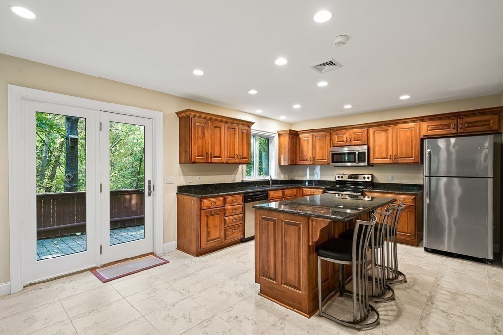 22 McCall Road Winchester, MA 01890 - Photo 34 of 40 a kitchen with stainless steel appliances granite countertop a refrigerator a sink a stove and island