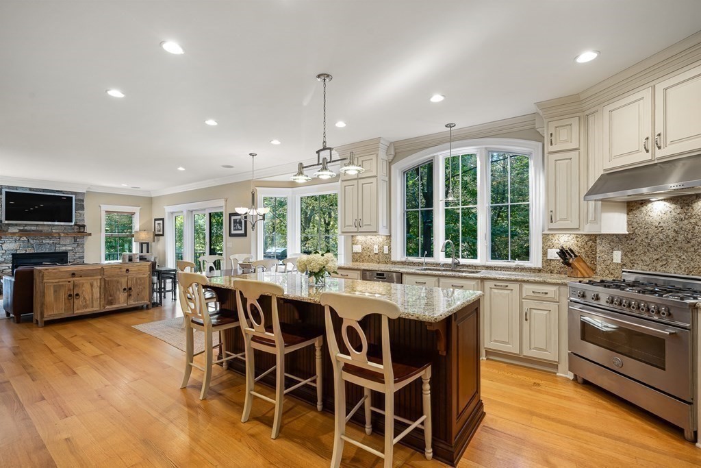 22 McCall Road Winchester, MA 01890 - Photo 10 of 40 a kitchen with stainless steel appliances granite countertop a stove top oven a sink dishwasher a dining table and chairs with wooden floor
