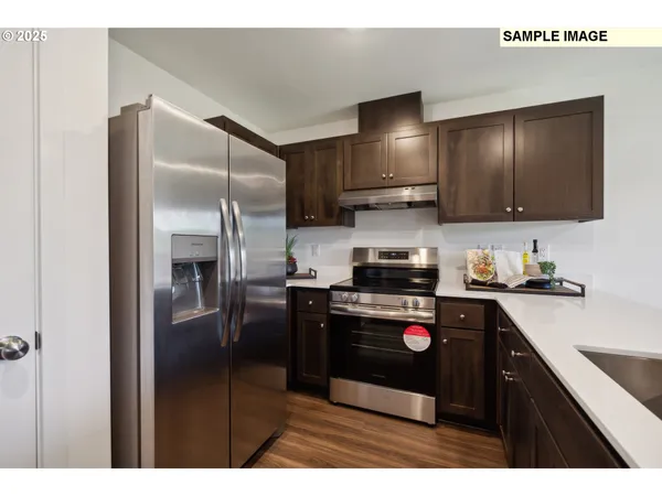 a kitchen with stainless steel appliances granite countertop a refrigerator a stove and a sink