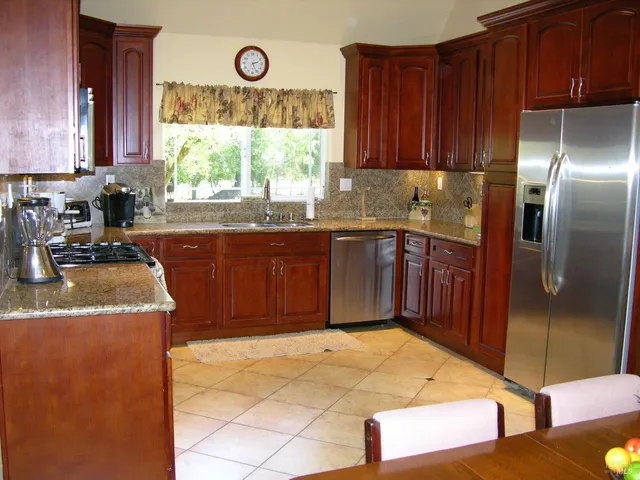 a kitchen with stainless steel appliances granite countertop a sink dishwasher stove and refrigerator