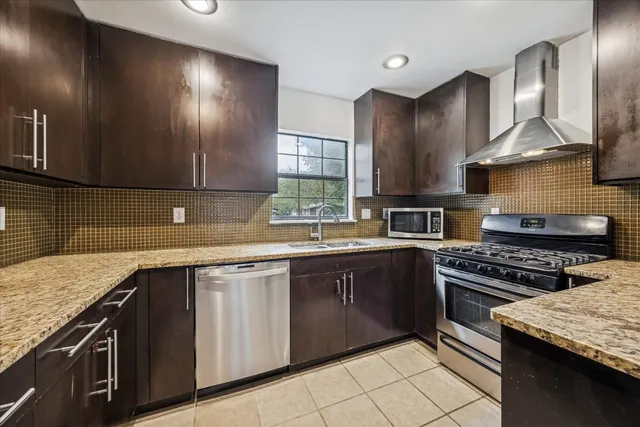 a kitchen with stainless steel appliances kitchen island granite countertop a refrigerator and a sink
