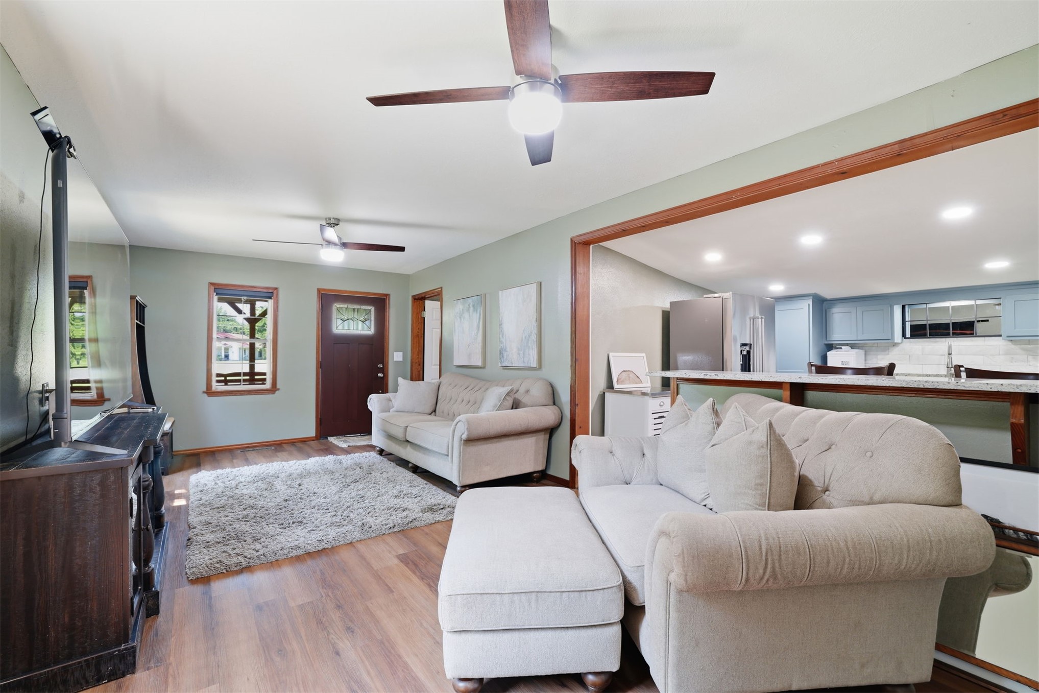 210 Main Caddo, OK 74729 - Photo 6 of 30 Open-concept living area with wood-finish flooring, two ceiling fans, and a pass-through to the kitchen
