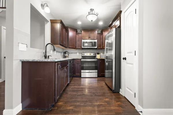 a large kitchen with stainless steel appliances granite countertop a sink and cabinets