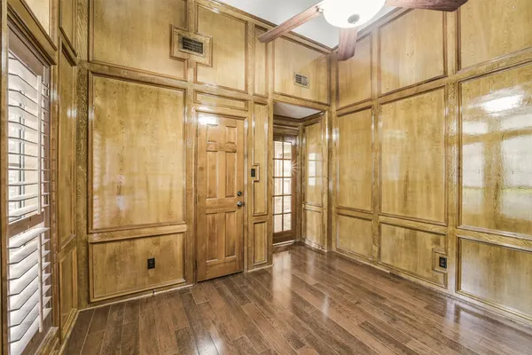 an empty room with wooden floor and windows