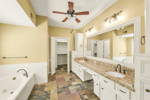 a spacious bathroom with a granite countertop tub double vanity sink and a mirror