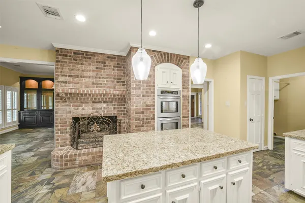 a kitchen with kitchen island granite countertop a stove and a wooden floor